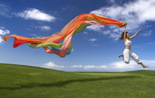 Kobieta skacząca z kolorową szarfą